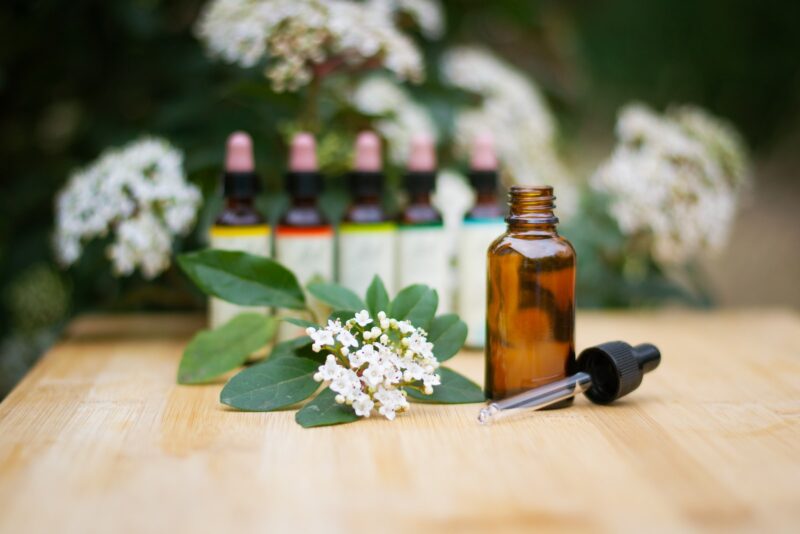 a bottle of essential oils sitting on a table next to a bunch of flowers